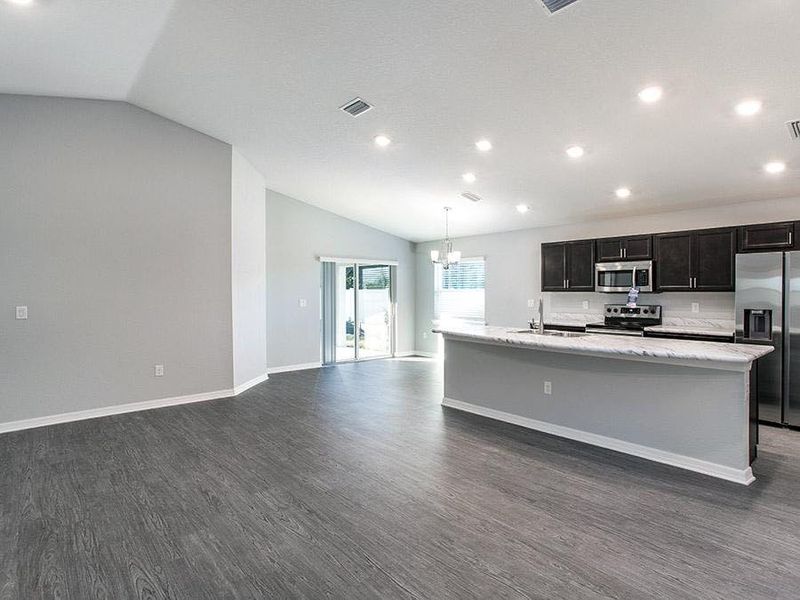 Open living flows under an airy volume ceiling with luxury vinyl plank flooring - Photo showcases a home with similar finishes. Colors and design options in actual home for sale may differ.