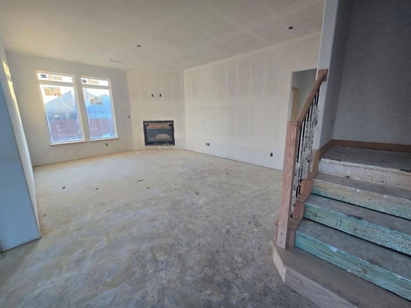 Unfurnished living room featuring a fireplace and stairway