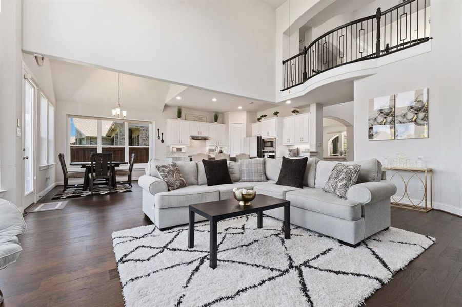 Living room featuring a high ceiling, a chandelier, and dark wood-type flooring