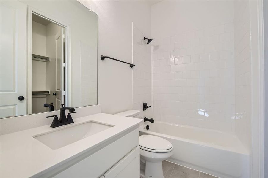 Full bathroom featuring vanity, tiled shower / bath combo, toilet, and tile patterned floors