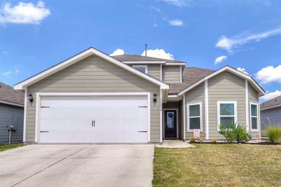 View of front of property featuring a front lawn, an attached garage, driveway, and roof with shingles