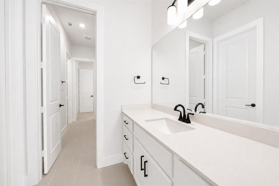Bathroom vanity featuring a light-colored countertop, integrated sink, and matte black faucet
