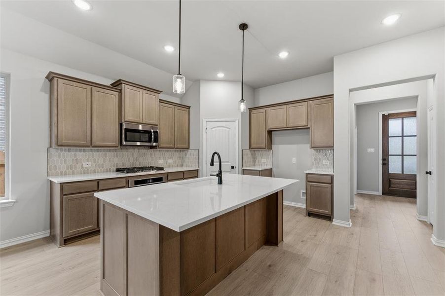 Kitchen featuring a large central island with a white countertop and a matte black gooseneck faucet