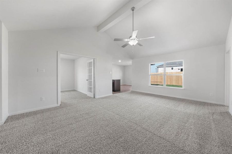 Unfurnished living room featuring beam ceiling, light colored carpet, high vaulted ceiling, and ceiling fan