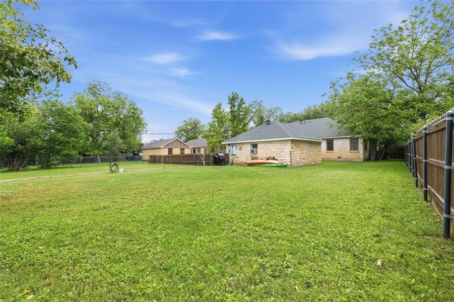 Expansive green lawn with a wood privacy fence and mature trees defining the property lines Expansive green lawn with a wood privacy fence and mature trees defining the property lines