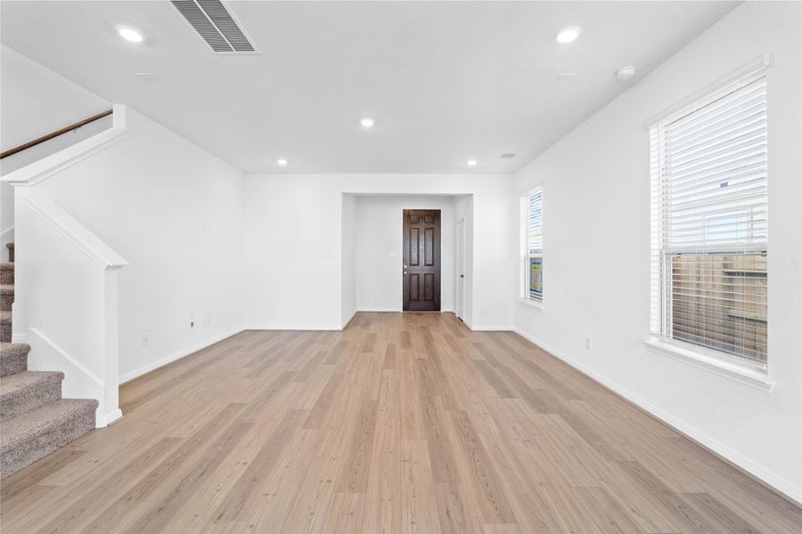 Bring family and friends together in this beautiful family room! It features high ceilings, recessed lighting, custom paint, stunning Layton Lake vinyl plank flooring in Soft Beige, and large windows that fill the space with natural light all day long.