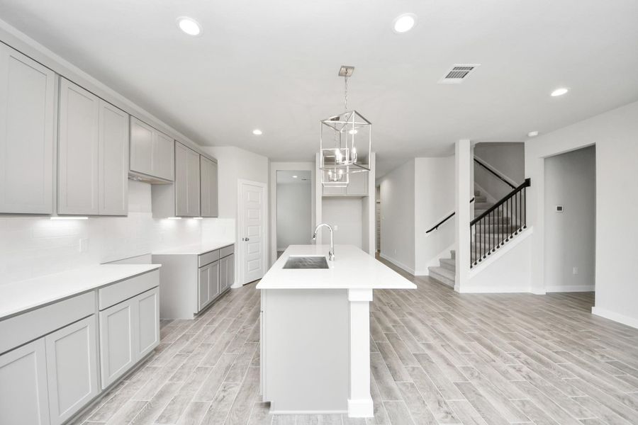 The kitchen is a culinary haven, featuring granite countertops, a tile backsplash, stainless steel appliances, 42” upper cabinets, and undercabinet lighting. Sample photo of completed home with similar floor plan. Actual colors and selections may vary.