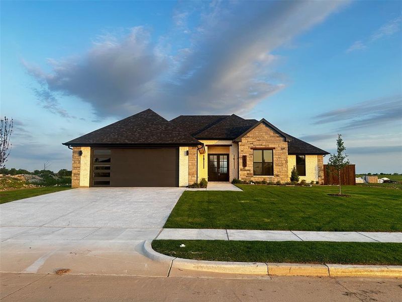 Prairie-style house featuring a front lawn, driveway, french doors, an attached garage, and roof with shingles
