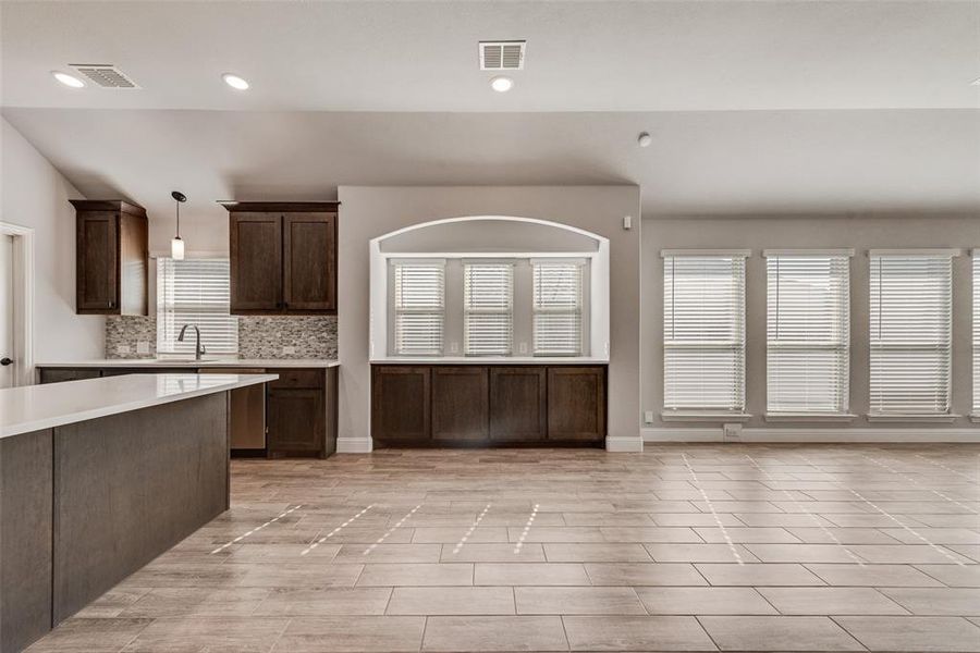 Kitchen featuring dark brown cabinetry, pendant lighting, recessed lighting, backsplash, and wood tiled floors Kitchen featuring dark brown cabinetry, pendant lighting, recessed lighting, backsplash, and wood tiled floors