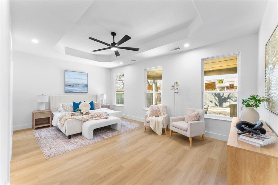 Bedroom with a raised ceiling, light wood-style floors, ceiling fan, and recessed lighting