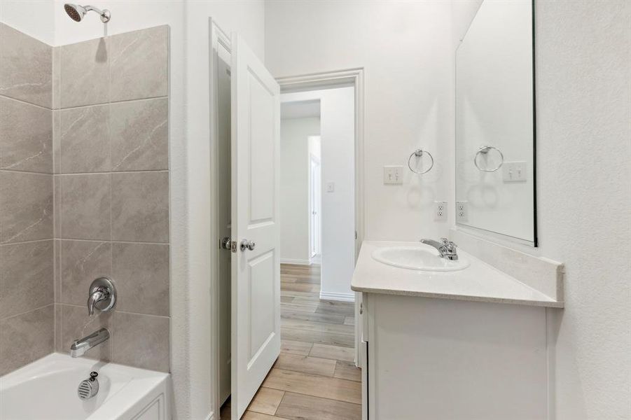 Bathroom featuring vanity, tiled shower / bath, and wood-type flooring