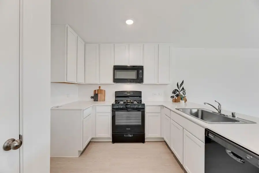 Kitchen with black appliances, light countertops, white cabinetry, light wood finished floors, and a peninsula