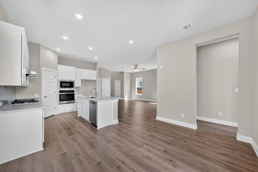 Kitchen with open floor plan, white cabinets, recessed lighting, a center island with sink, and a ceiling fan Kitchen with open floor plan, white cabinets, recessed lighting, a center island with sink, and a ceiling fan