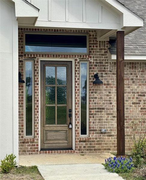 Entrance to property with brick siding and roof with shingles