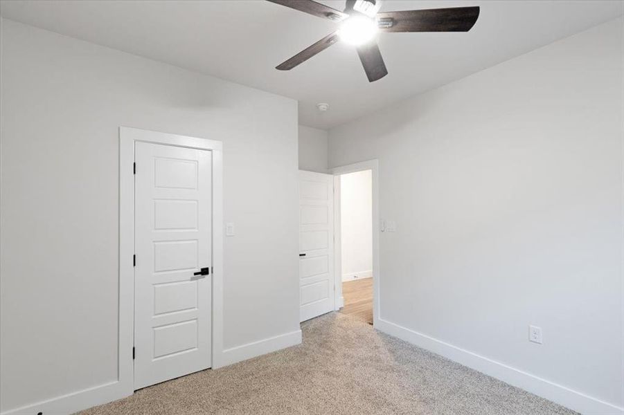 Unfurnished bedroom featuring light colored carpet and ceiling fan