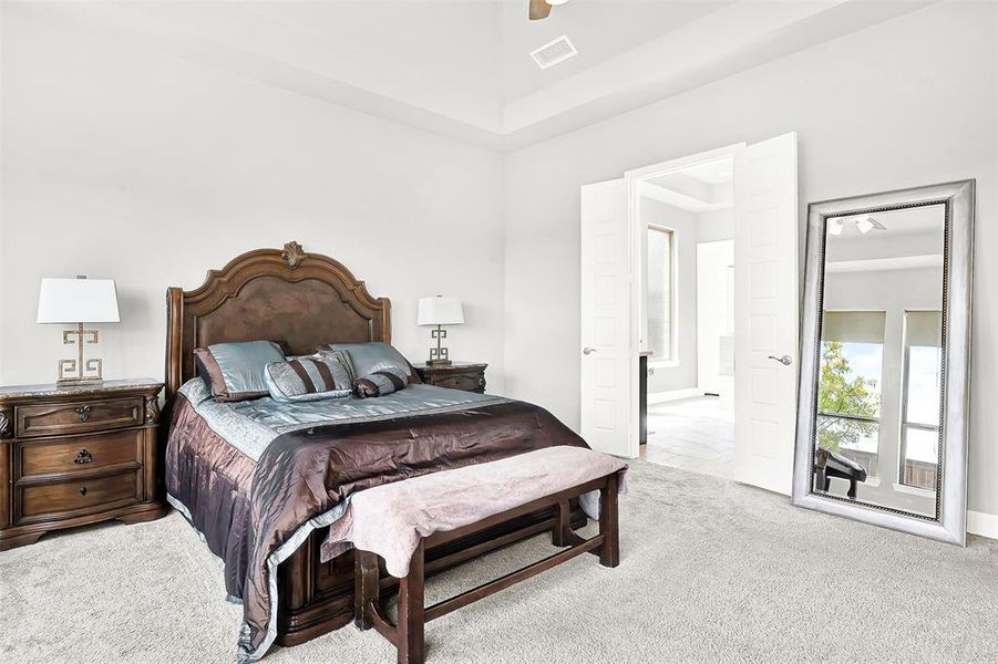 Bedroom featuring light carpet, ceiling fan, and a towering ceiling