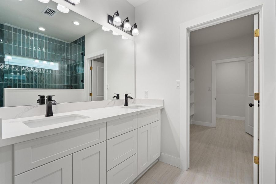 Dual sink vanity with white cabinetry, quartz countertops, and matte black fixtures