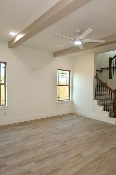 The living room features two large windows, a ceiling fan, stylish beams, and luxury vinyl flooring. The living room features two large windows, a ceiling fan, stylish beams, and luxury vinyl flooring.