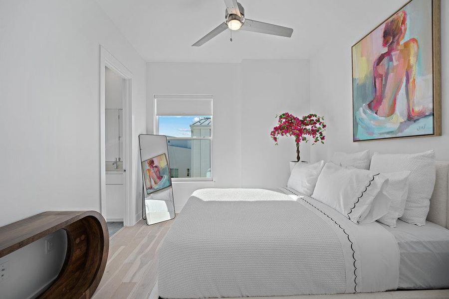 Bedroom with wood finished floors, a ceiling fan, and connected bathroom