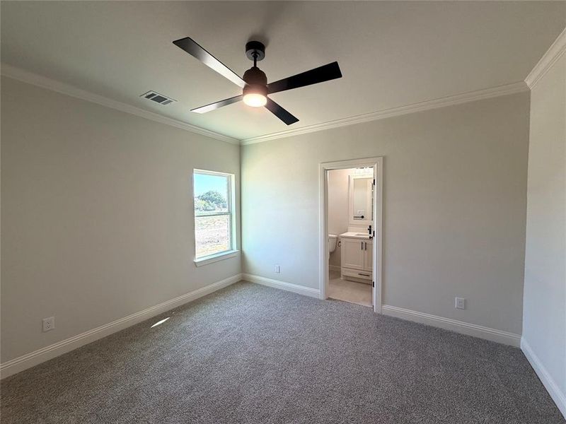 Unfurnished bedroom with ornamental molding, light carpet, a ceiling fan, and ensuite bathroom Unfurnished bedroom with ornamental molding, light carpet, a ceiling fan, and ensuite bathroom