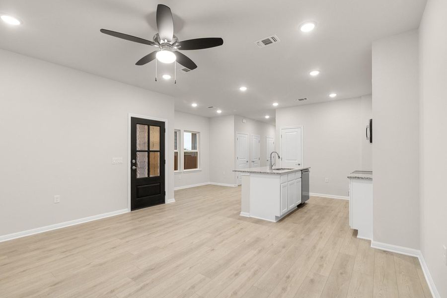 Open concept living area featuring light-colored flooring, a ceiling fan with integrated lighting, and recessed lighting