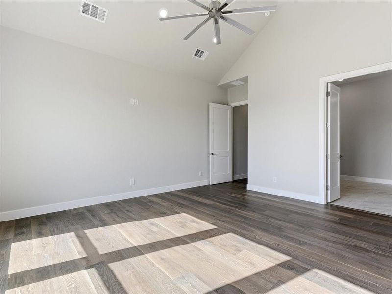 Unfurnished bedroom with high vaulted ceiling, wood finished floors, and ceiling fan