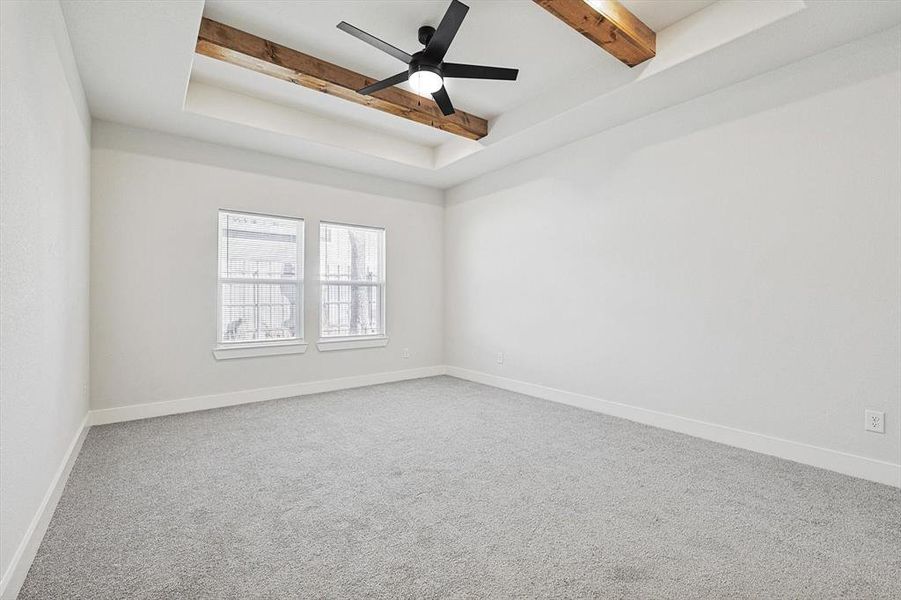 Empty room featuring ceiling fan, beam ceiling, and carpet floors