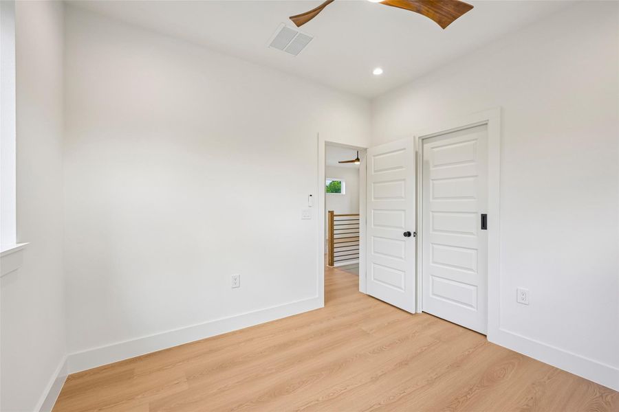 Blonde wood flooring and bright white walls define this airy, ready-to-personalize bedroom.
