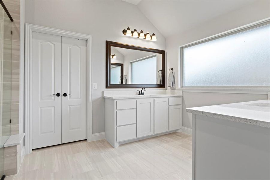 Bathroom featuring tile patterned flooring, vanity, lofted ceiling, and a shower with shower door