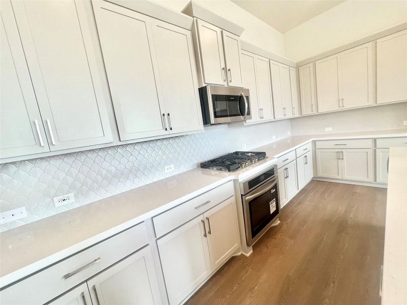 Kitchen featuring wood finished floors, light countertops, and appliances with stainless steel finishes Kitchen featuring wood finished floors, light countertops, and appliances with stainless steel finishes