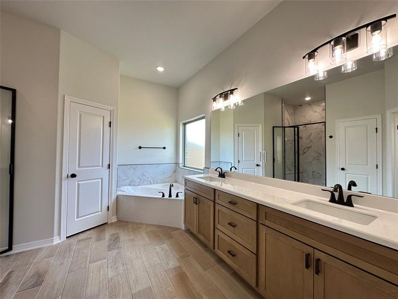 Full bath featuring a marble finish shower, double vanity, a bath, wood tiled floors, and recessed lighting