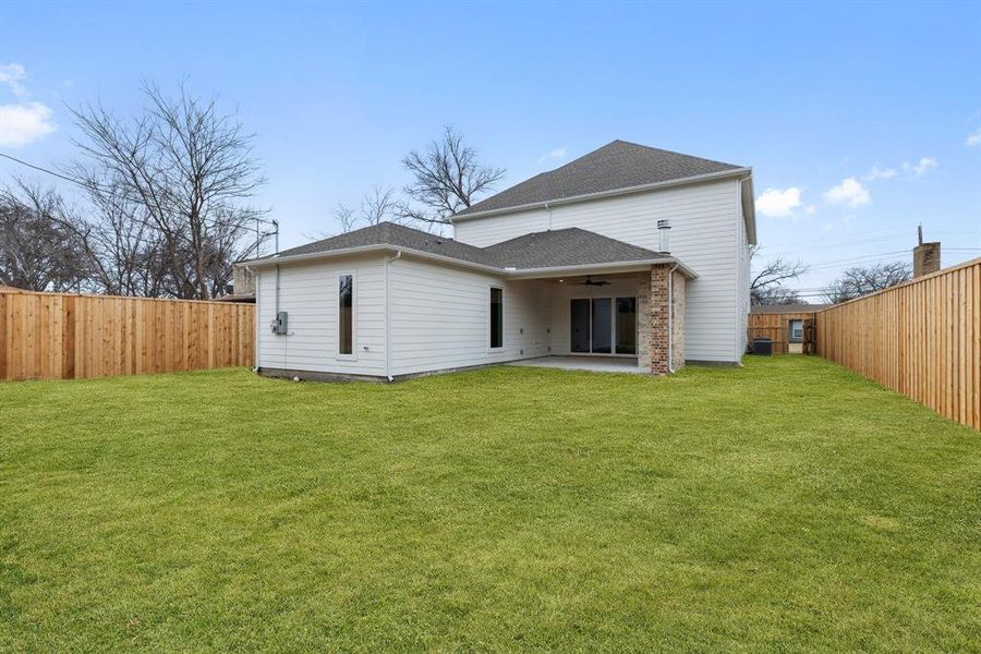 Back of house with ceiling fan, a patio area, and a yard