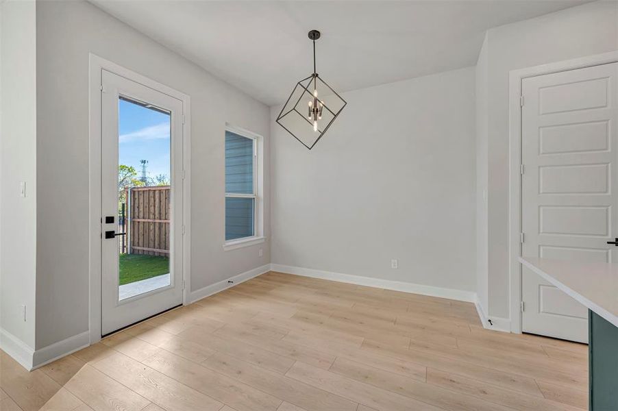 Unfurnished dining area featuring suspended lighting and light wood-style floors Unfurnished dining area featuring suspended lighting and light wood-style floors