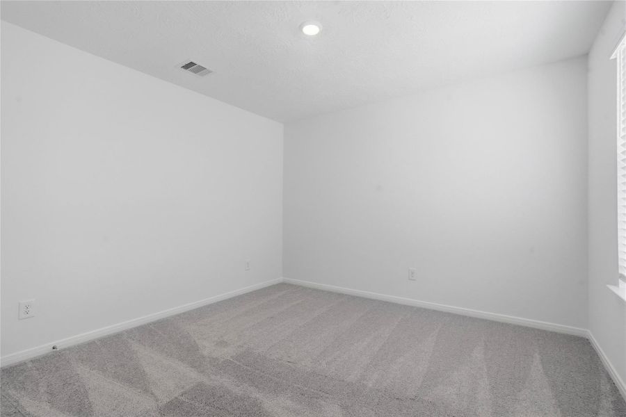 This secondary bedroom combines comfort and style, featuring plush carpeting, neutral paint, recessed lighting, a large window with blinds, and a spacious closet. This secondary bedroom combines comfort and style, featuring plush carpeting, neutral paint, recessed lighting, a large window with blinds, and a spacious closet.