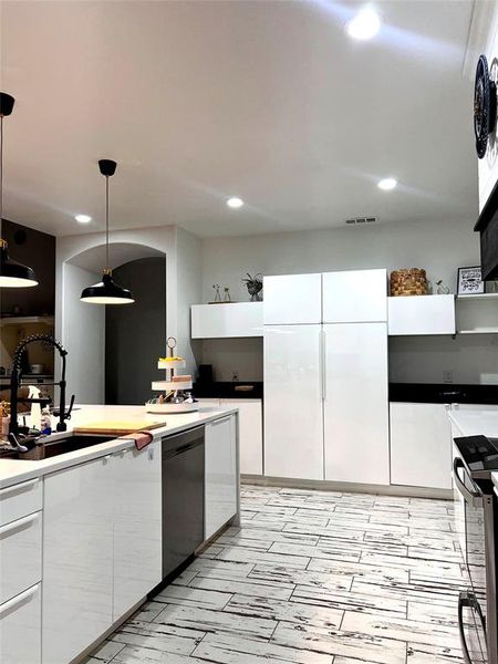 Kitchen with sink, hanging light fixtures, dishwasher, stove, and white cabinets