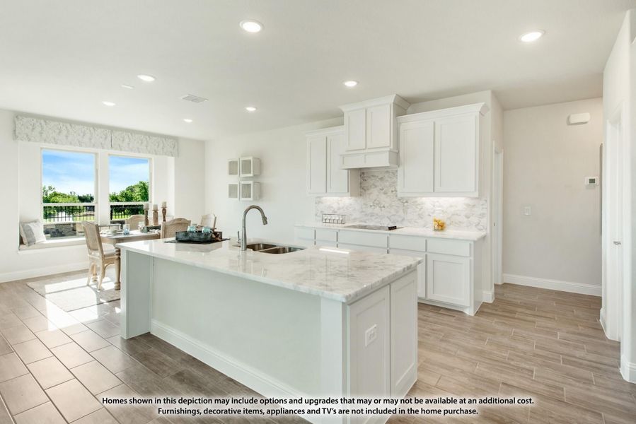 Open kitchen with white cabinets, marble island with sink, and wood-look tile floors open to dining area