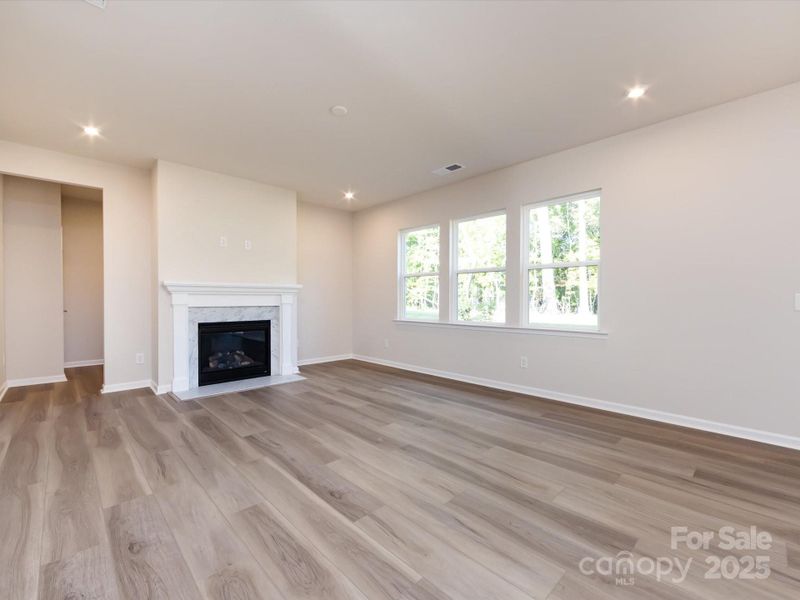 Great room with large bright windows and electric fireplace.
