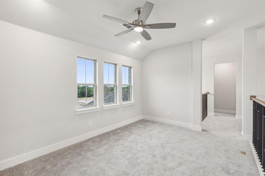 Carpeted empty room with ceiling fan and lofted ceiling