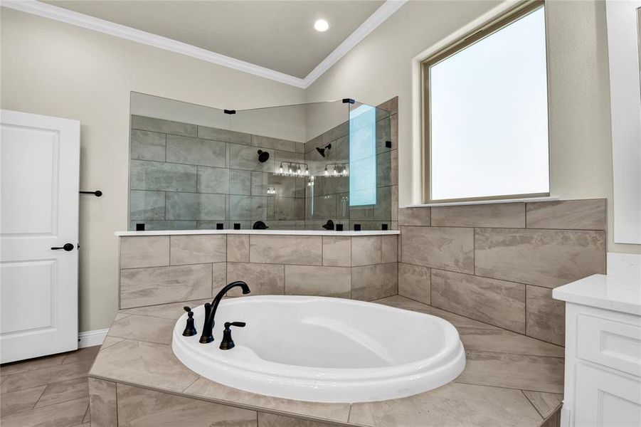 Bathroom with a wealth of natural light, independent shower and bath, crown molding, and vanity