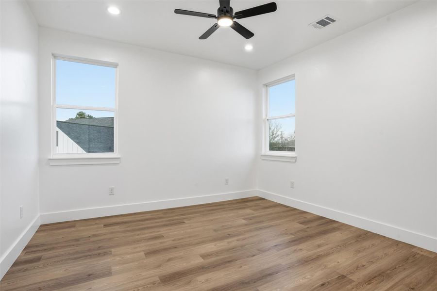Empty room with wood finished floors, ceiling fan, plenty of natural light, and recessed lighting