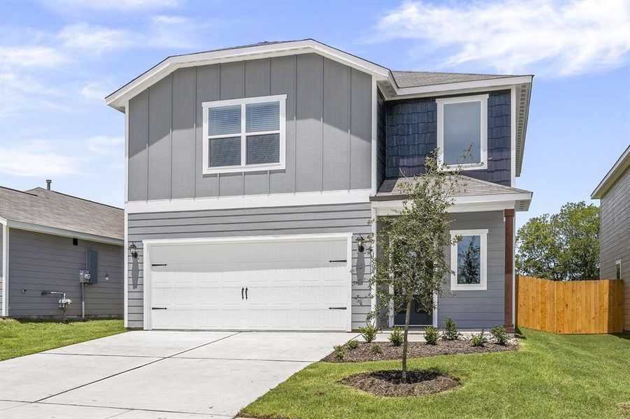 View of front of property featuring a garage and a front lawn