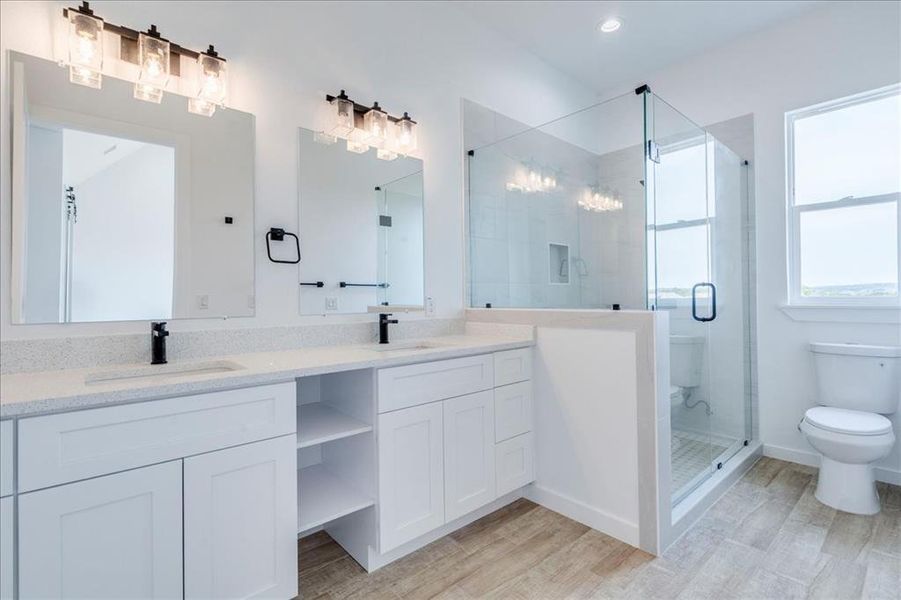 Dual vanities and a spacious glass-enclosed shower create a pristine and functional primary bathroom retreat. Dual vanities and a spacious glass-enclosed shower create a pristine and functional primary bathroom retreat.