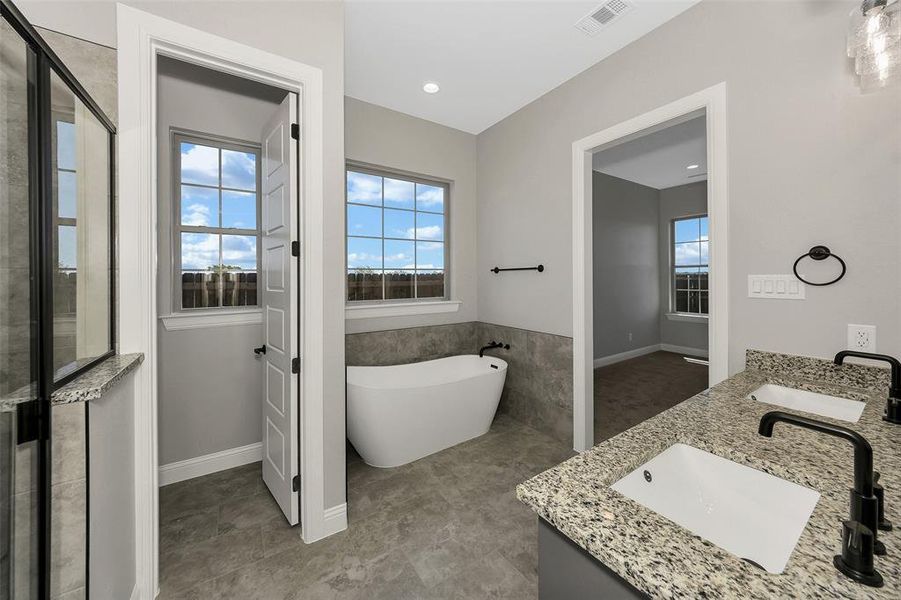 Bathroom with a freestanding tub, double vanity, a stall shower, and recessed lighting