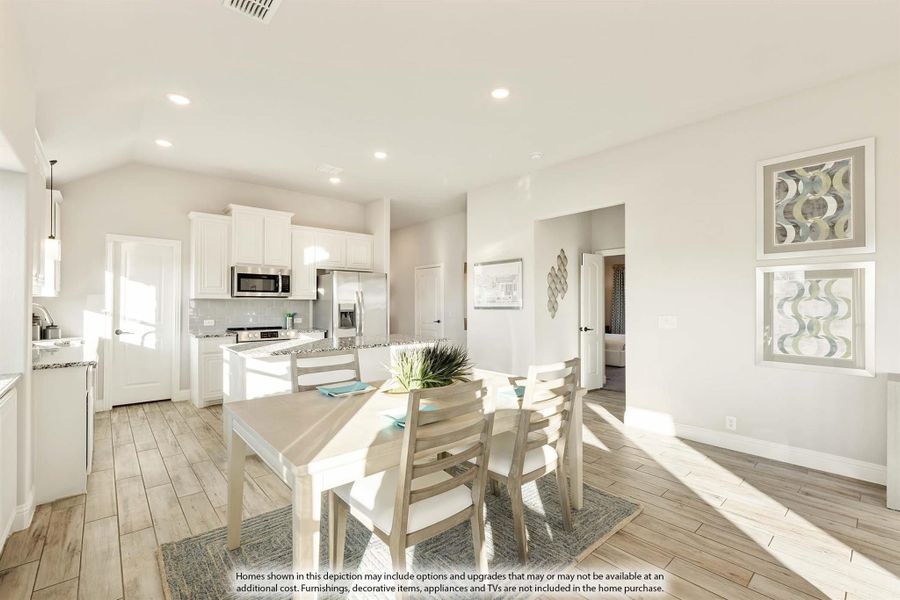 Open dining area with wood-look floors adjoining kitchen with white cabinets and stainless steel appliances Open dining area with wood-look floors adjoining kitchen with white cabinets and stainless steel appliances