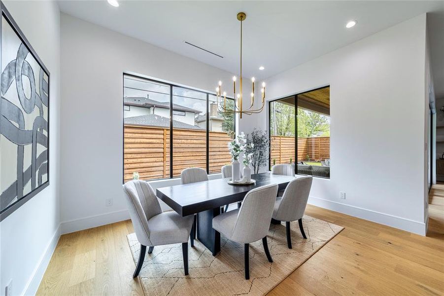 Dining area with light wood-style flooring and suspended lighting