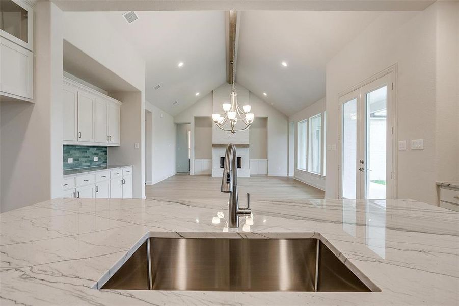 Kitchen featuring pendant lighting, sink, beam ceiling, and white cabinets