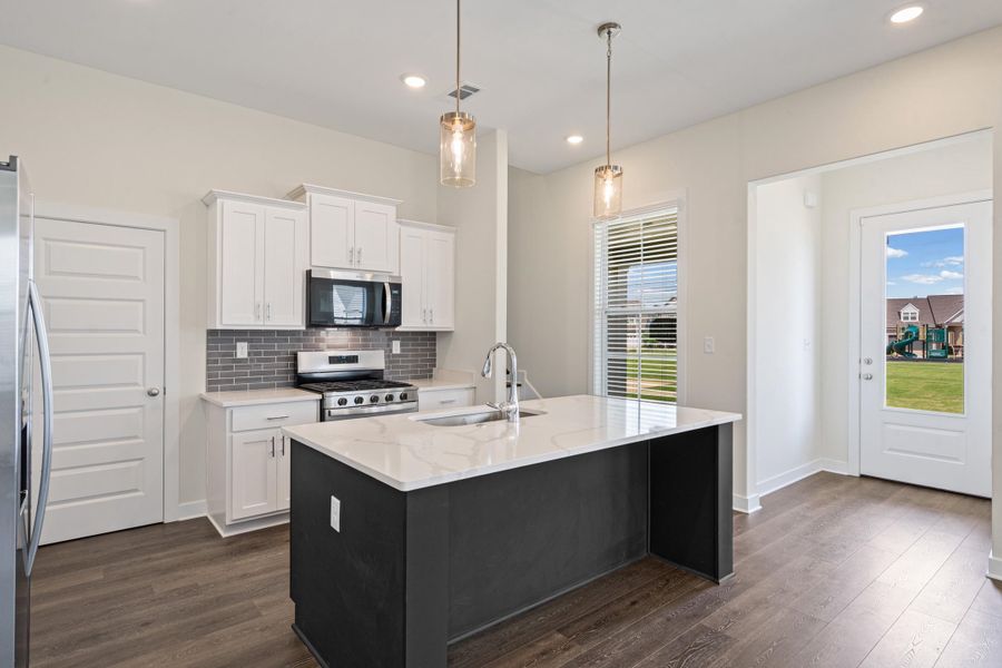 Kitchen featuring a dark-toned island with a light countertop, white cabinetry, and stainless steel appliances Kitchen featuring a dark-toned island with a light countertop, white cabinetry, and stainless steel appliances