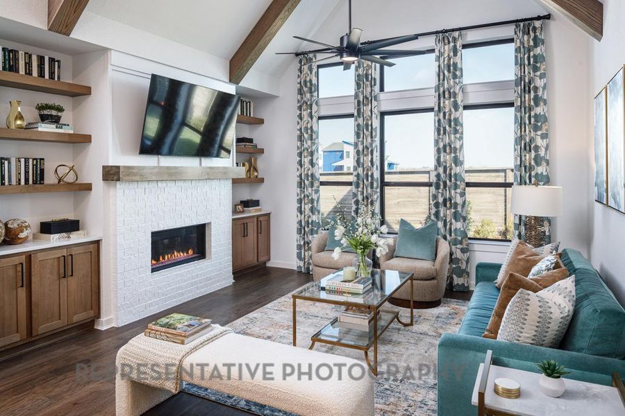 Living area featuring a glass covered fireplace, ceiling fan, and dark wood finished floors