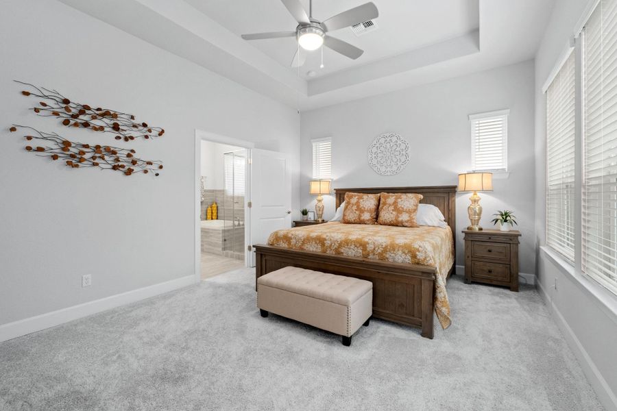 Bedroom with multiple windows, light carpet, connected bathroom, and visible vents Bedroom with multiple windows, light carpet, connected bathroom, and visible vents