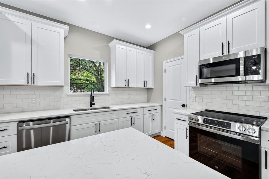 Kitchen with stainless steel appliances, white cabinetry, light stone countertops, and recessed lighting Kitchen with stainless steel appliances, white cabinetry, light stone countertops, and recessed lighting